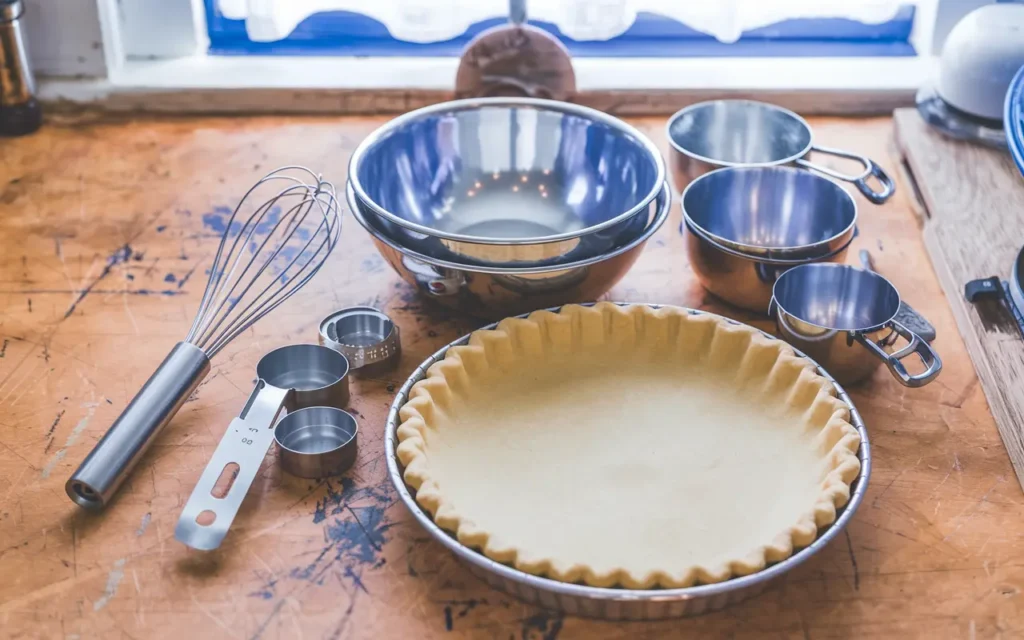 Essential baking tools for Milk Bar Pumpkin Pie, featuring a pie pan, whisk, and mixing bowls