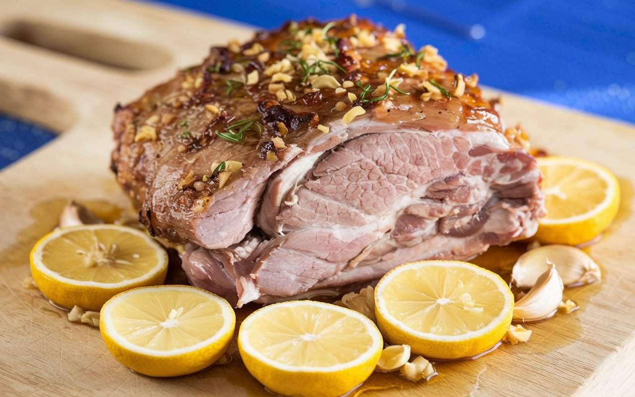 A photo of a lemon honey garlic roast pork with zesty flavors. The pork is browned and slightly crispy on the outside